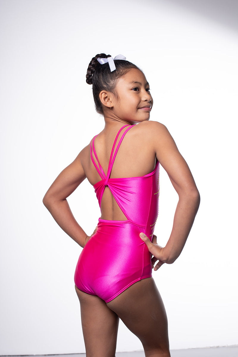 Photo of a 10 year old girl infront of a white background wearing a bright hot pink sheen leotard. The front features jelly yellow crystals, and the back has 4 thin straps twisted through a gathered back opening creating a traingle. 