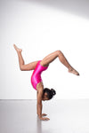 Photo of a 10 year old girl infront of a white background wearing a bright hot pink sheen leotard. The front features jelly yellow crystals, and the back has 4 thin straps twisted through a gathered back opening creating a traingle. 