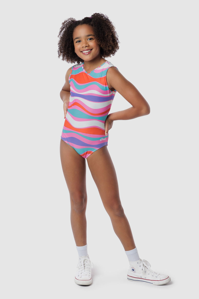 Photo of a 5 year old girl, standing iPhoto of a 10 year old girl standing infront of a white backdrop. Wearing a wavy pattern gymnastics leotard that is a mix of purple, aqua, white & purple. There are no crystals, making it great for training.
