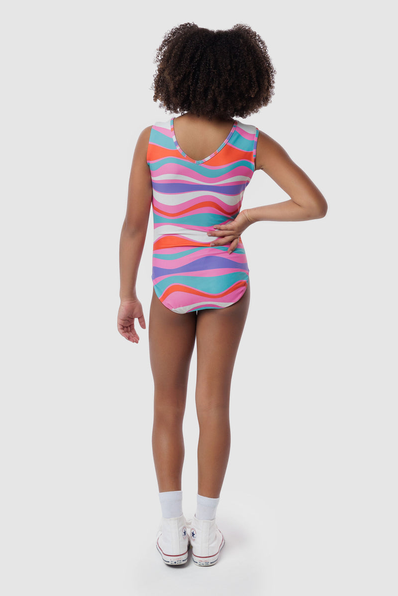 Photo of a 5 year old girl, standing iPhoto of a 10 year old girl standing infront of a white backdrop. Wearing a wavy pattern gymnastics leotard that is a mix of purple, aqua, white & purple. There are no crystals, making it great for training.
