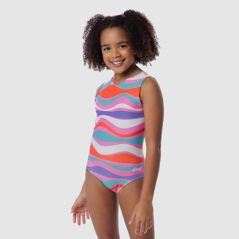 Photo of a 5 year old girl, standing iPhoto of a 10 year old girl standing infront of a white backdrop. Wearing a wavy pattern gymnastics leotard that is a mix of purple, aqua, white & purple. There are no crystals, making it great for training.