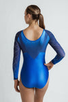 Photo of a girl infront of a grey backdrop, wearing a long sleeve gymnastics competition leotard. The leotard is a mixture of royal blue & navy blue. The royal blue lower gives off a nice sheen, and the upper is an ombre from light to dark with lots of crystal detailing. The sleeves are long with heavy two colour crystal detailing in a criss cross pattern. Extremely sparkly leotard. 