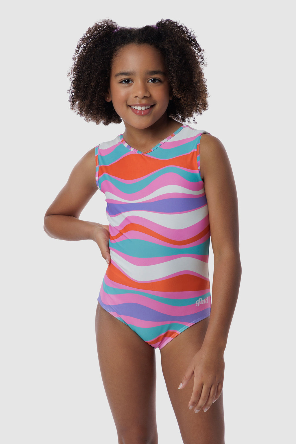 Photo of a 5 year old girl, standing iPhoto of a 10 year old girl standing infront of a white backdrop. Wearing a wavy pattern gymnastics leotard that is a mix of purple, aqua, white & purple. There are no crystals, making it great for training.
