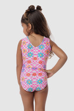 Photo of a 5 year old girl, standing infront of a white backdrop. Wearing a patterned leotard that has pink & white checkers with green, orange & purple flowers ontop. There are no crystals, making it great for training.