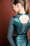 Photo of a 12 year old girl standing infront of a terracotta backdrop. Wearing a deep Green and black Girls Gymnastics long sleeve WAG Competition Leotard by GMD Activewear Australia. 